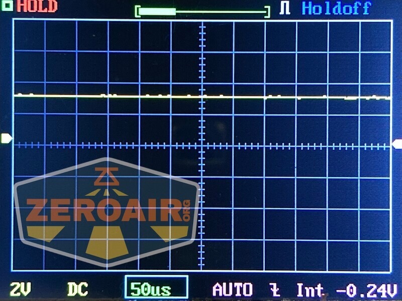 A digital oscilloscope screen displays a mostly flat yellow waveform with minor fluctuations. The display shows a 2V scale, 50 microseconds per division, and AUTO mode. The Zeroair logo is overlaid in the lower left corner.