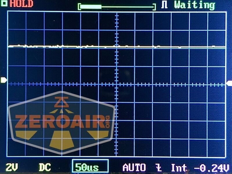 An oscilloscope screen displays a mostly flat waveform near zero, with the word Waiting in the top right. The ZeroAir.org logo is visible in the lower left corner. Settings at the bottom show 2V, DC, 50us, AUTO, Int, and -0.24V.