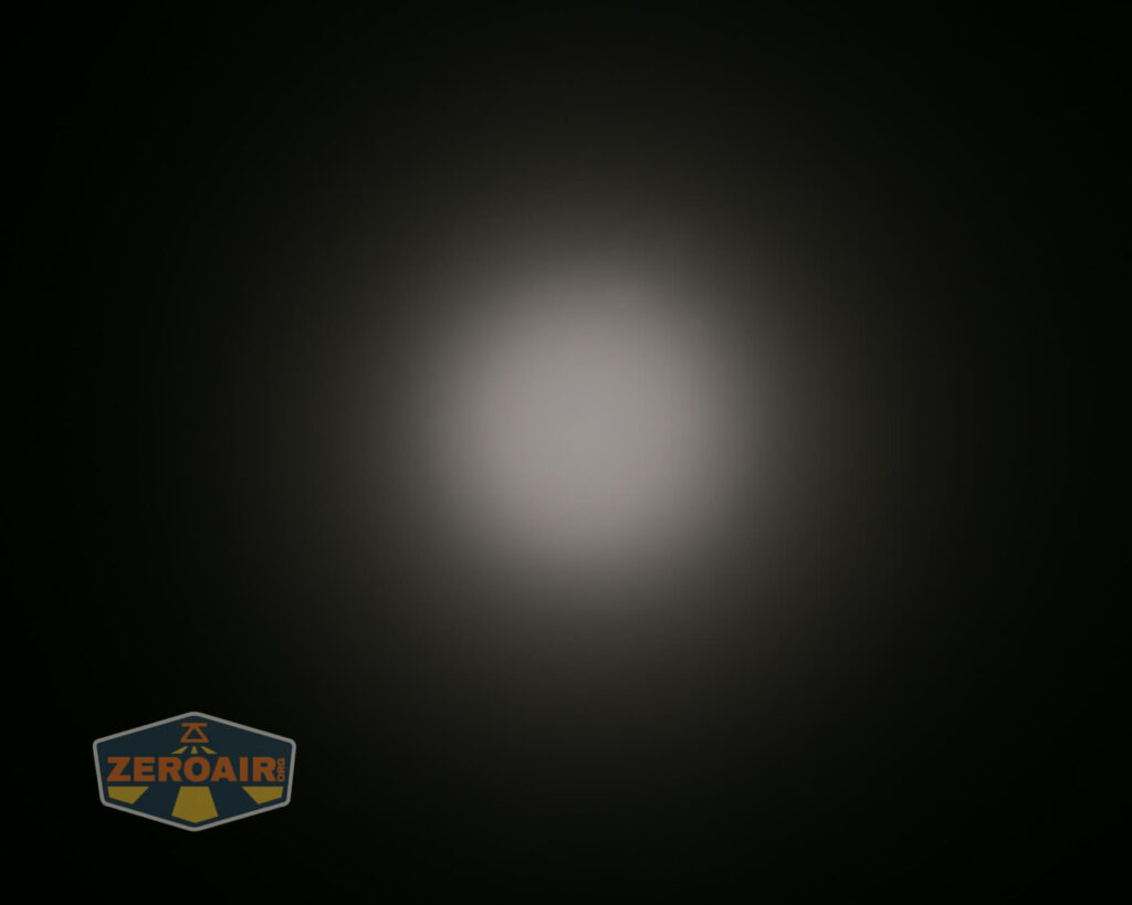A circular white light beam against a dark background, with a soft glow and diffuse edges. The ZeroAir logo appears in the lower left corner of the image.