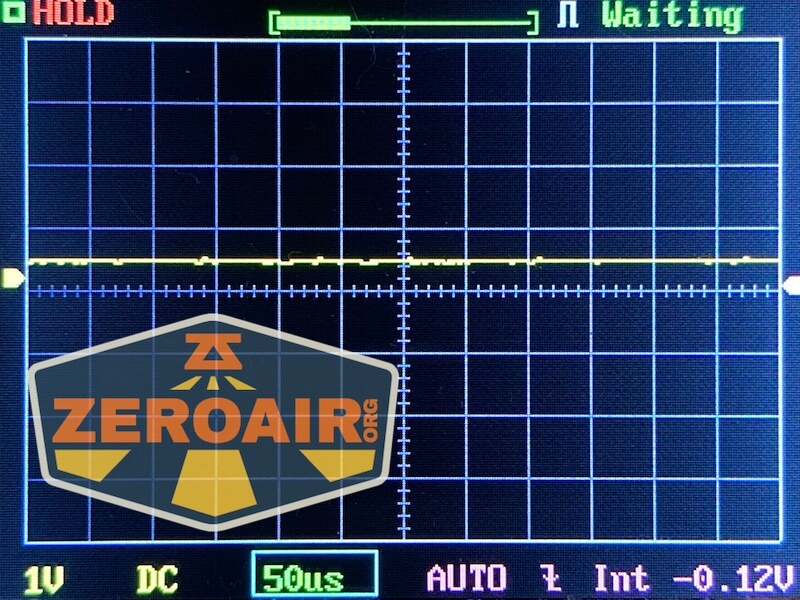 A digital oscilloscope screen shows a mostly flat yellow waveform with minor fluctuations. The display includes gridlines, measurement settings, and the words HOLD and Waiting at the top. The ZeroAir.org logo is overlaid.