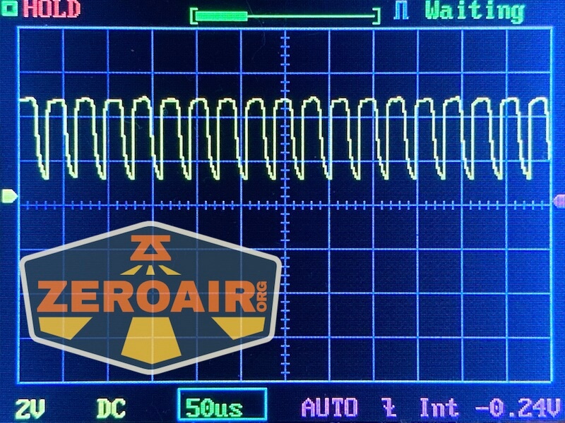 An oscilloscope screen displays a repeating yellow waveform with measurements indicated along the axes. The logo ZEROAIR.org is visible on the lower left of the screen.