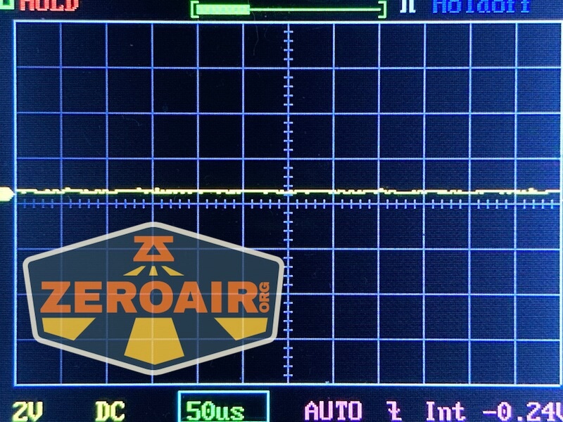 A digital oscilloscope screen displays a mostly flat yellow waveform near the center, indicating minimal signal variation. The logo ZEROAIR.org is overlaid on the lower left part of the image.