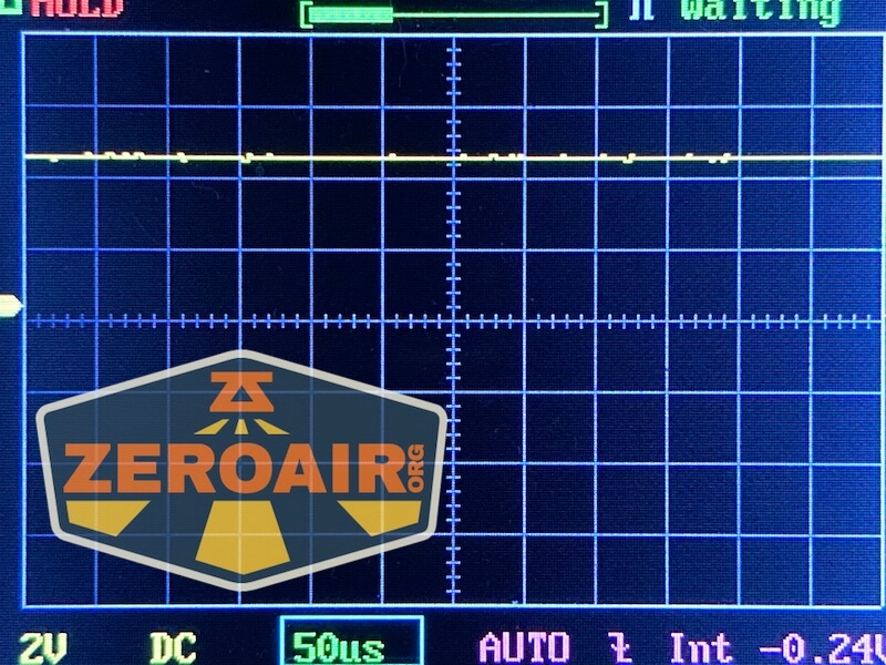 A digital oscilloscope screen shows a nearly flat yellow trace, gridlines, and measurement labels. The ZeroAir.org logo is overlaid in the lower left corner.