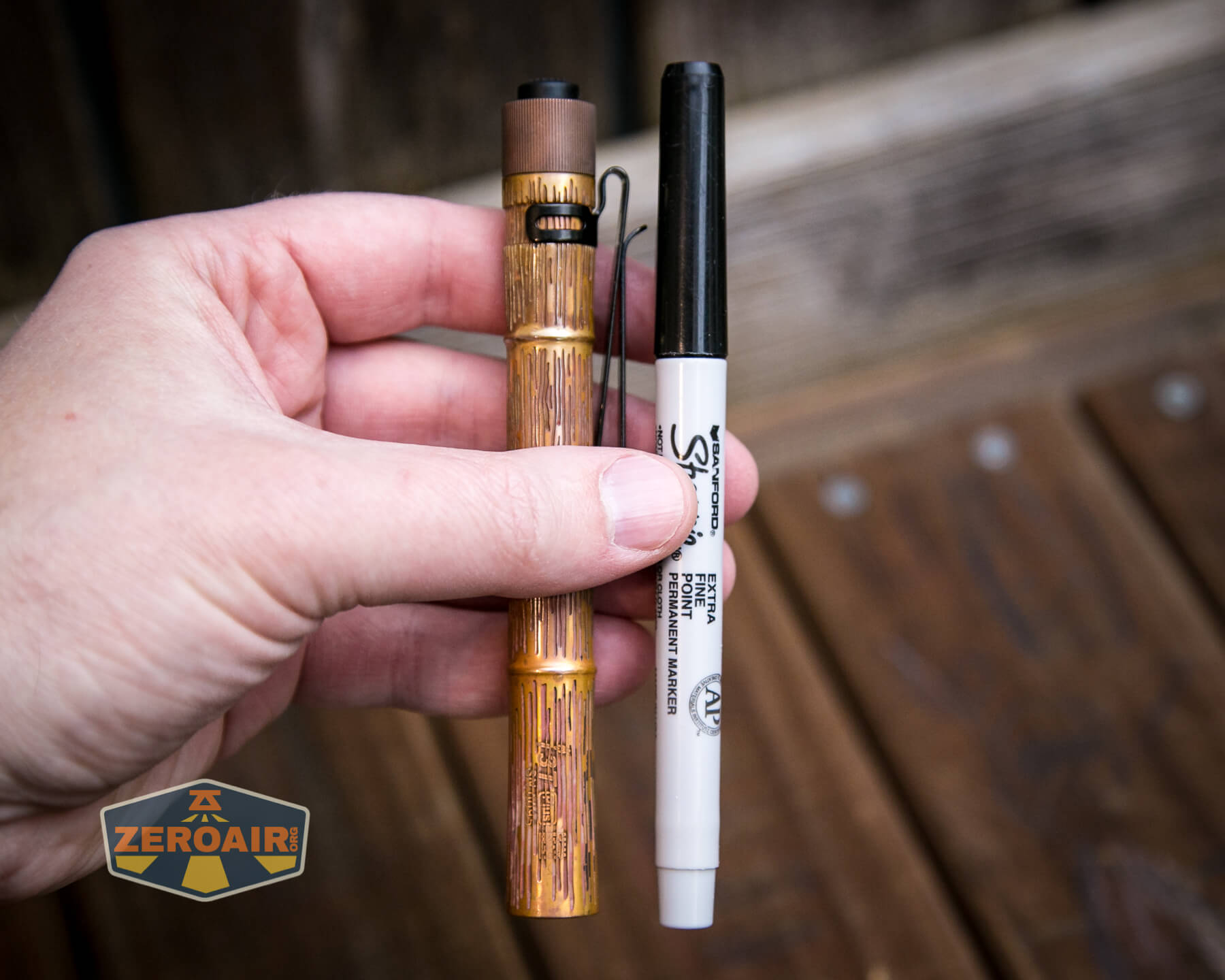 Olight i3T Plus Ancient Bamboo flashlight in hand beside Sharpie