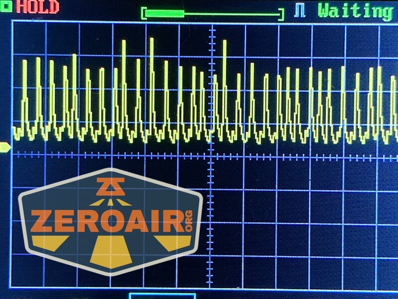 A digital oscilloscope screen displays a yellow waveform with sharp peaks and valleys. The words HOLD and Waiting appear at the top, and a ZEROAIR.ORG logo is overlaid in the lower-left corner.