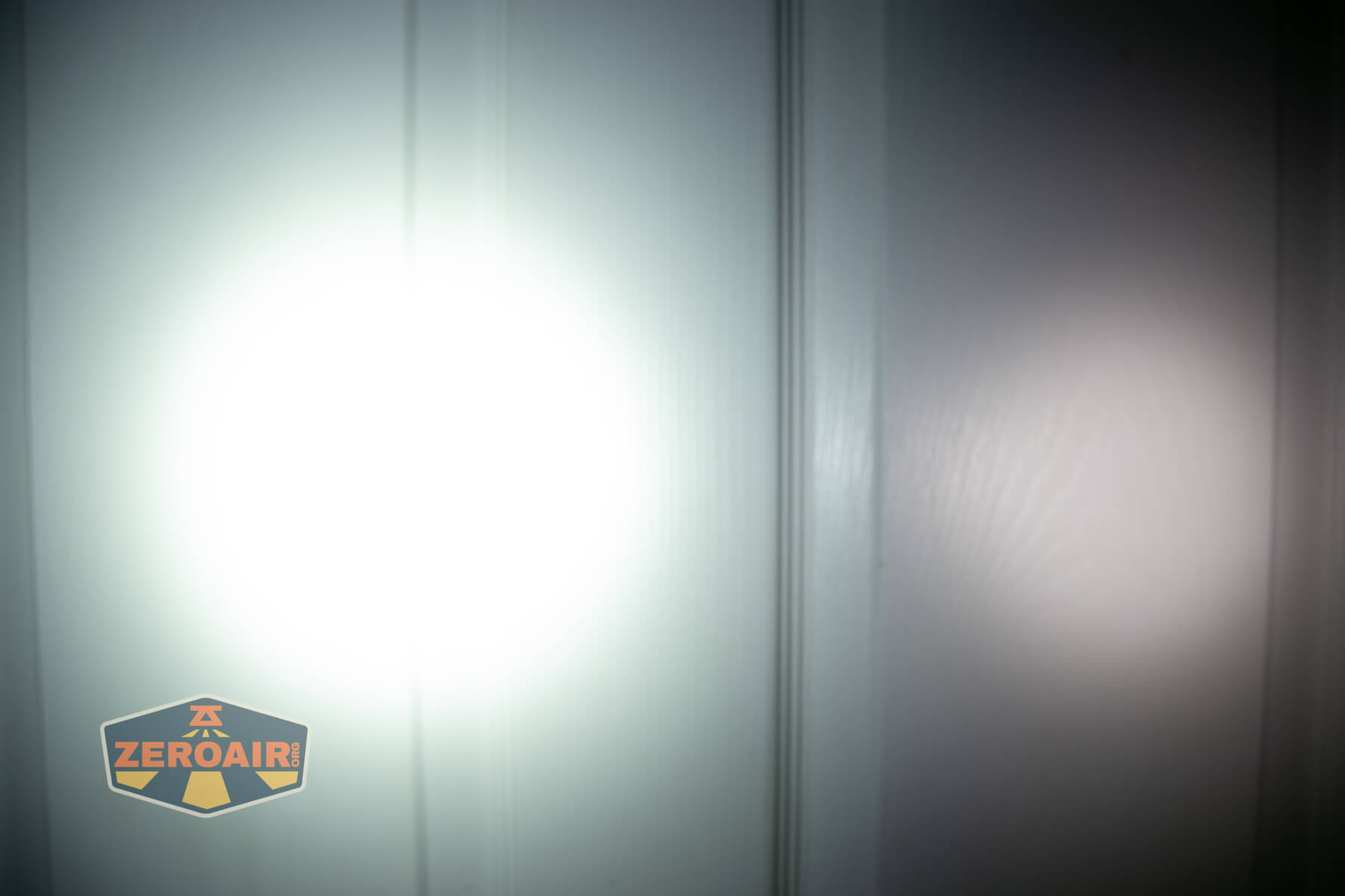 Olight i3E EOS flashlight beamshot on door compared to nichia 219b