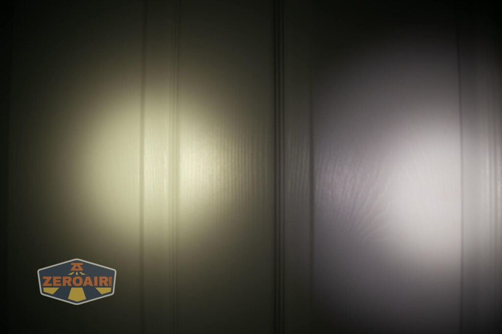 Two flashlight beams are shown on a vertically-grooved wall; the left beam is yellowish and warm, while the right beam is cooler and whiter. The ZeroAir logo is visible in the lower left corner.