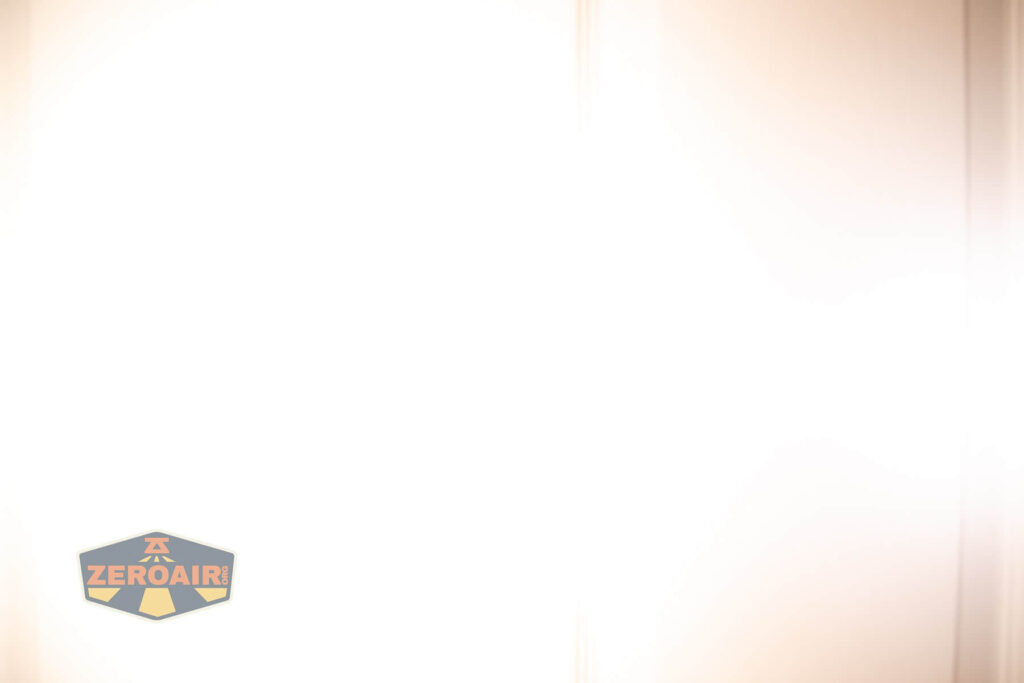 A mostly white, overexposed image with a faint logo in the lower left corner that reads ZEROAIR! inside a hexagon. The rest of the image is bright with some light tan vertical streaks.