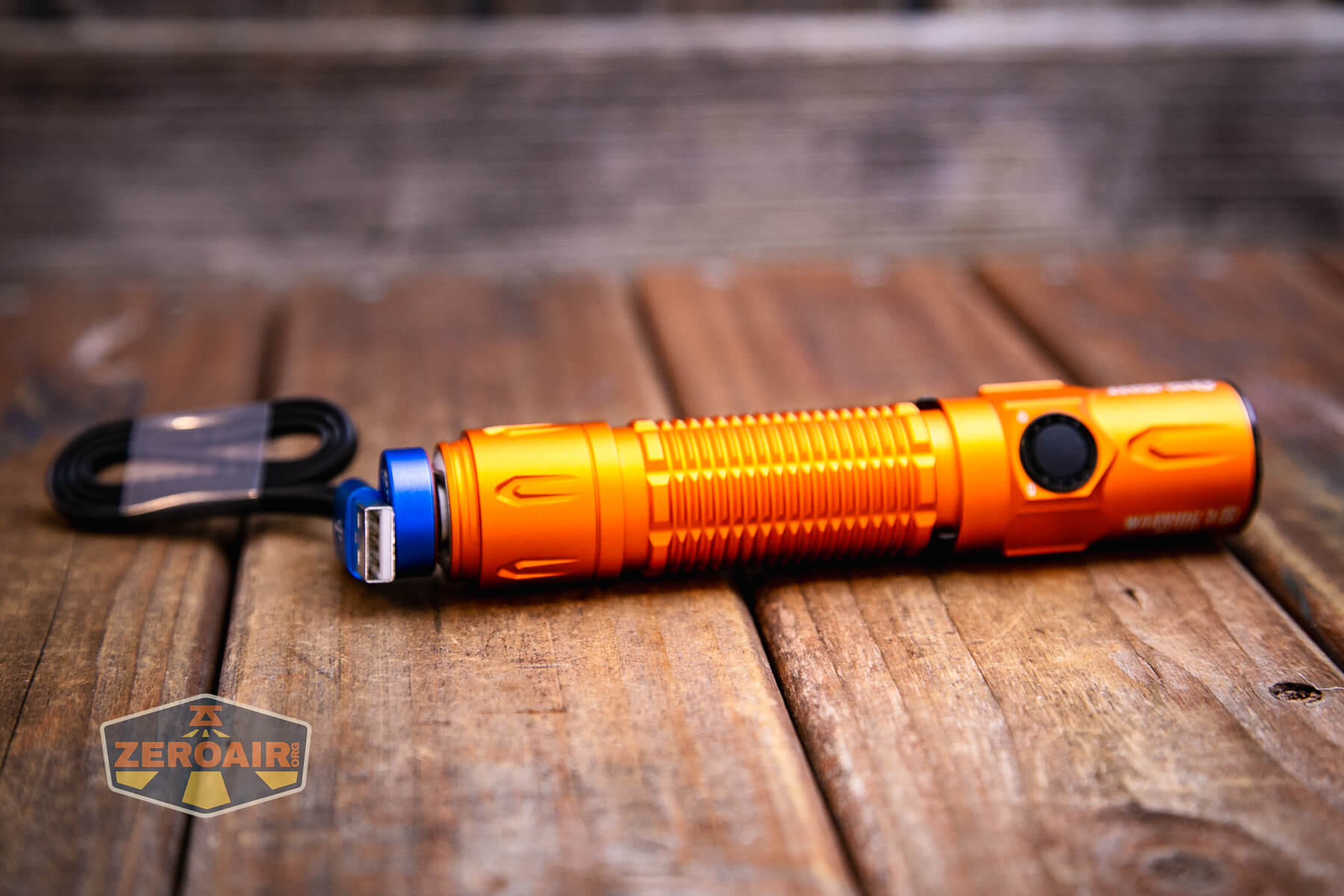 Olight Warrior 3S Orange flashlight on charging cable