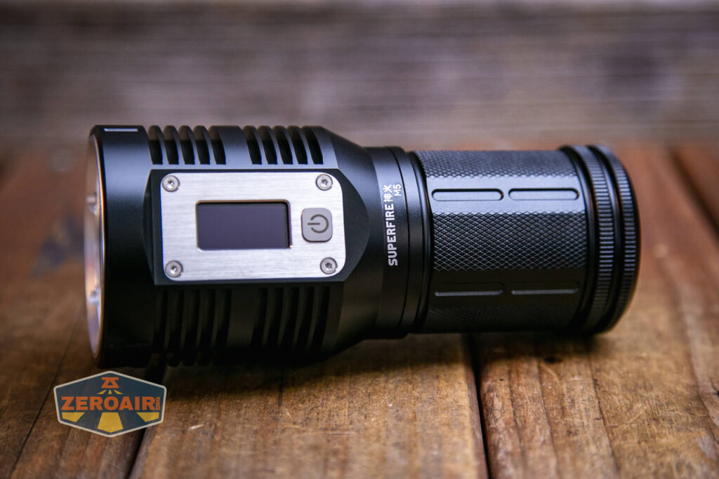 A black Superfire flashlight with a digital display and power button lies on a wooden surface. The ZeroAir logo appears in the bottom left corner of the image.