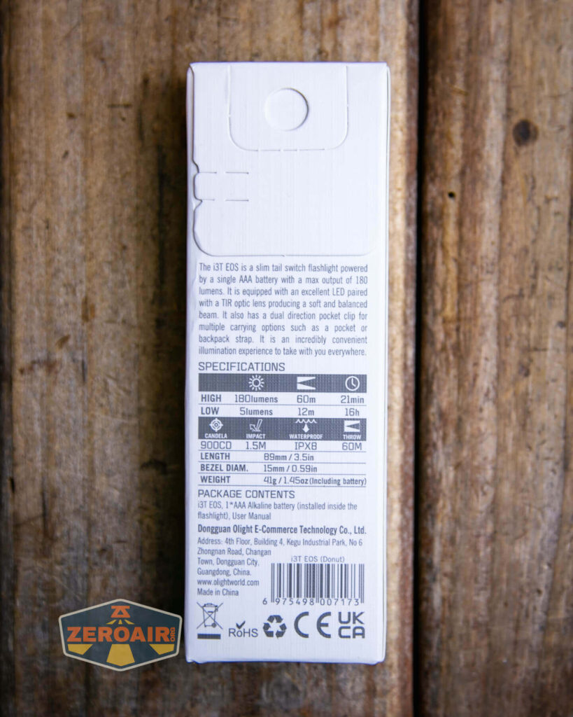 The back of a white flashlight box displays specifications and package contents, with text detailing brightness levels, beam distance, runtime, and manufacturer information, on a wooden surface. A ZEROAIR logo is in the lower left corner.