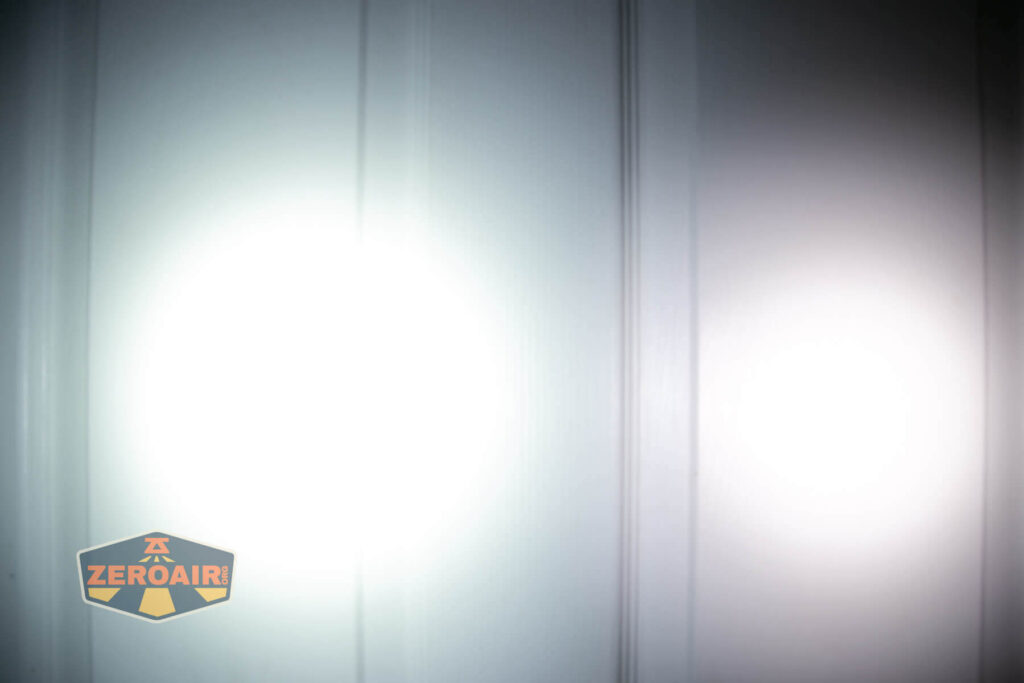 Two bright white flashlight beams are projected onto a white paneled door, creating overlapping circles of light. The ZeroAir logo is visible in the bottom left corner of the image.