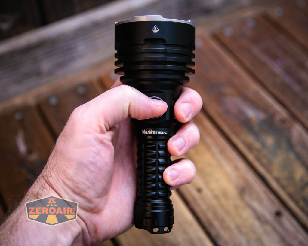 A hand holding a large, black Wurkkos TS30S Pro flashlight against a background of wooden planks. The ZeroAir logo is visible in the bottom left corner of the image.