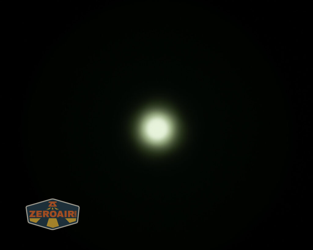 A bright, circular white light is centered against a dark black background. The light fades into a soft, greenish halo. A Zeroair logo is in the bottom left corner.