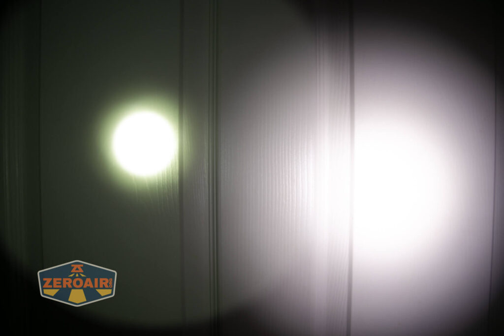 A close-up of a white paneled surface illuminated by two flashlight beams, one yellowish and the other white. A ZeroAir logo appears in the lower left corner.