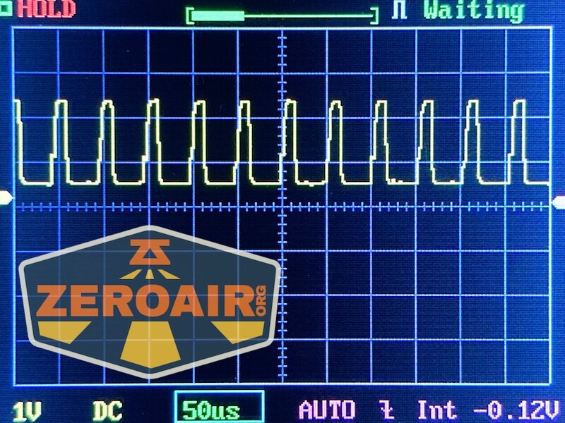 An oscilloscope screen shows a repeating square wave signal. The display includes gridlines, measurement values, and the ZeroAir logo partially covering the lower-left section.