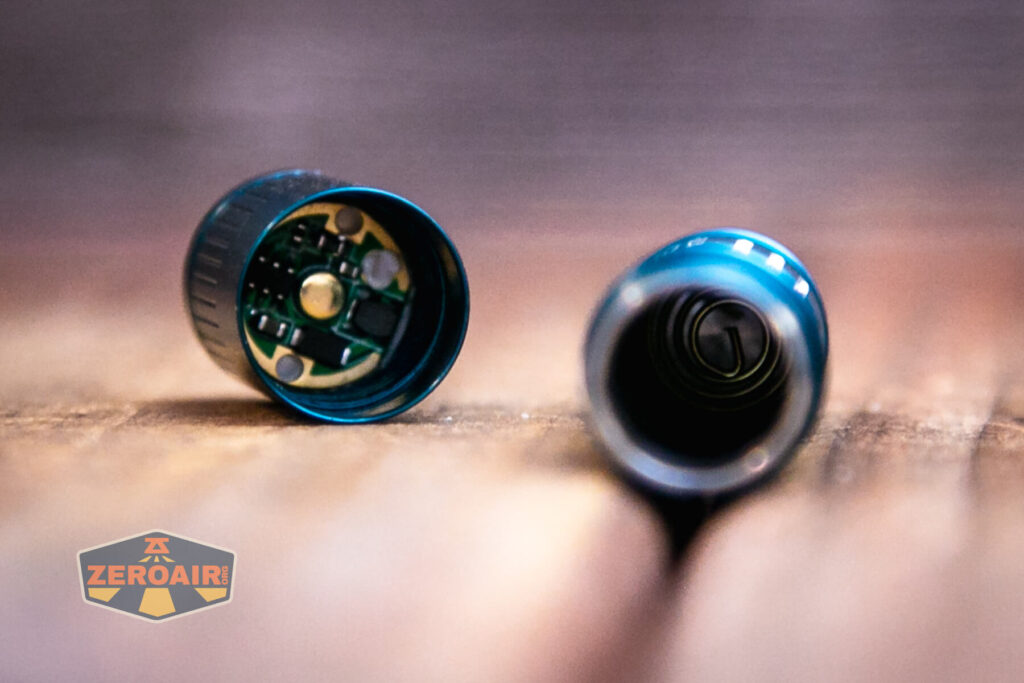 Olight i3E EOS AAA flashlight head off showing button and tail spring