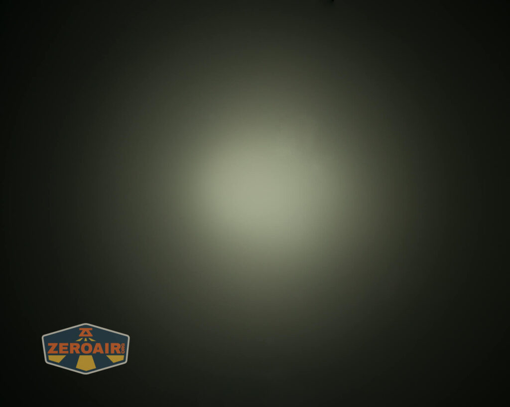 A circular beam of light is projected onto a dark surface, creating a gradient from bright center to darker edges. A logo with the text Zeroair appears in the bottom left corner.
