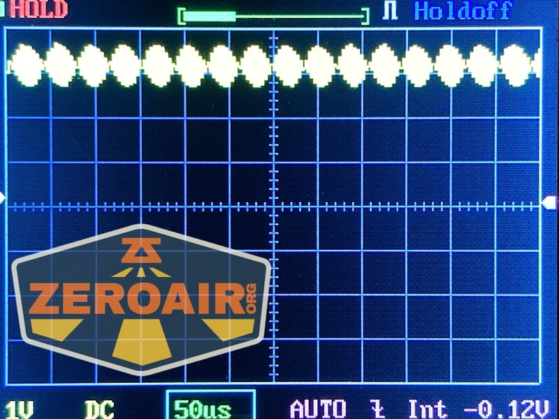 An oscilloscope screen displays a repeating waveform pattern. The lower left shows a yellow and gray ZeroAir logo. The settings indicate 1V, 50μs, AUTO, Int, and -0.12V offset.