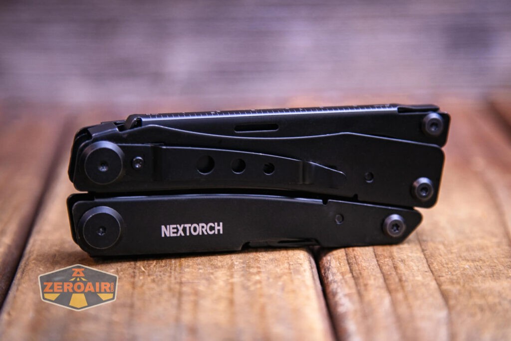 A black Nextorch MT10 multi-tool labeled NEXTORCH is folded closed and resting on a wooden surface. The tool’s design and details are clearly visible, with a ZEROAIR logo in the bottom left corner.
