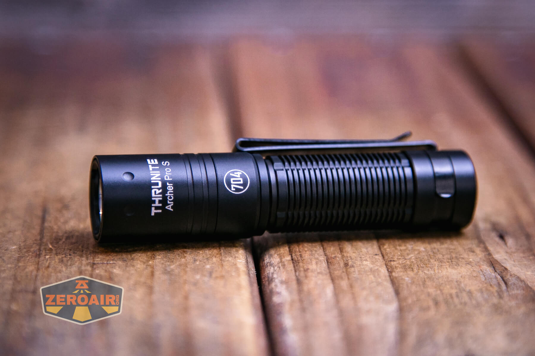 A ThruNite Archer Pro S Flashlight with a pocket clip rests on a wooden surface. The ZeroAir logo is visible in the bottom left corner of the image.