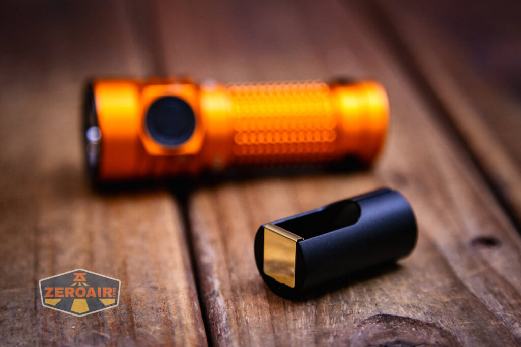 Olight Baton Turbo Orange flashlight beside included CR123 adapter