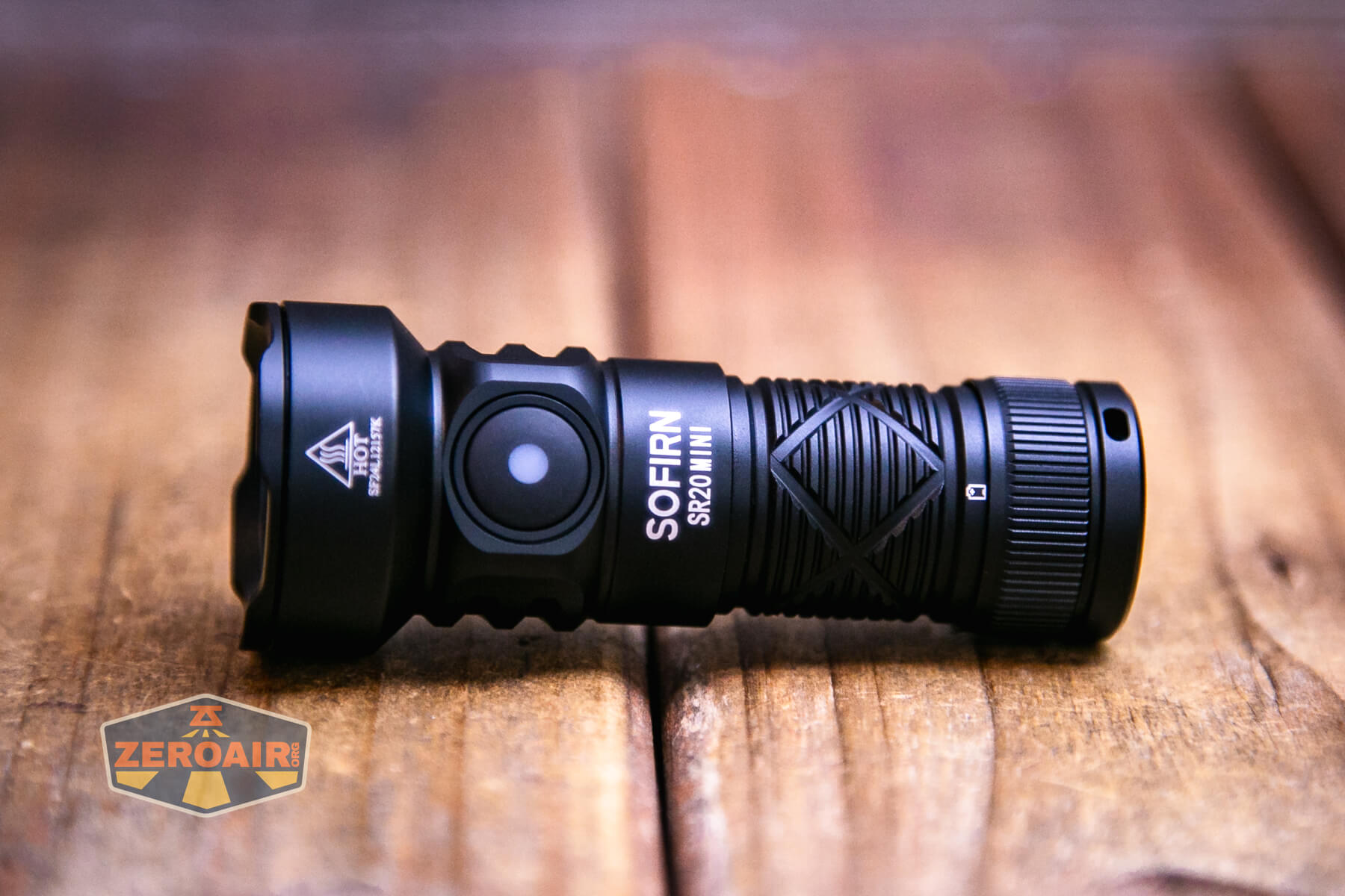 A black Sofirn SR20 Mini EDC flashlight rests on a wooden surface, highlighting its textured grip and side button. The ZeroAir logo appears in the bottom left corner of the image.