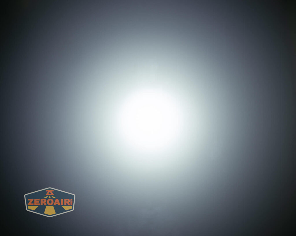 A bright white light is centered against a dark, gradient background. In the lower left corner, there is a shield-shaped logo with the text ZEROAIR in orange.