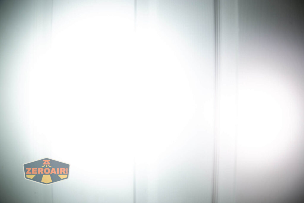 Nitecore HC65 UHE headlamp beamshots on door (at 1') compared to nichia 219b 4500K