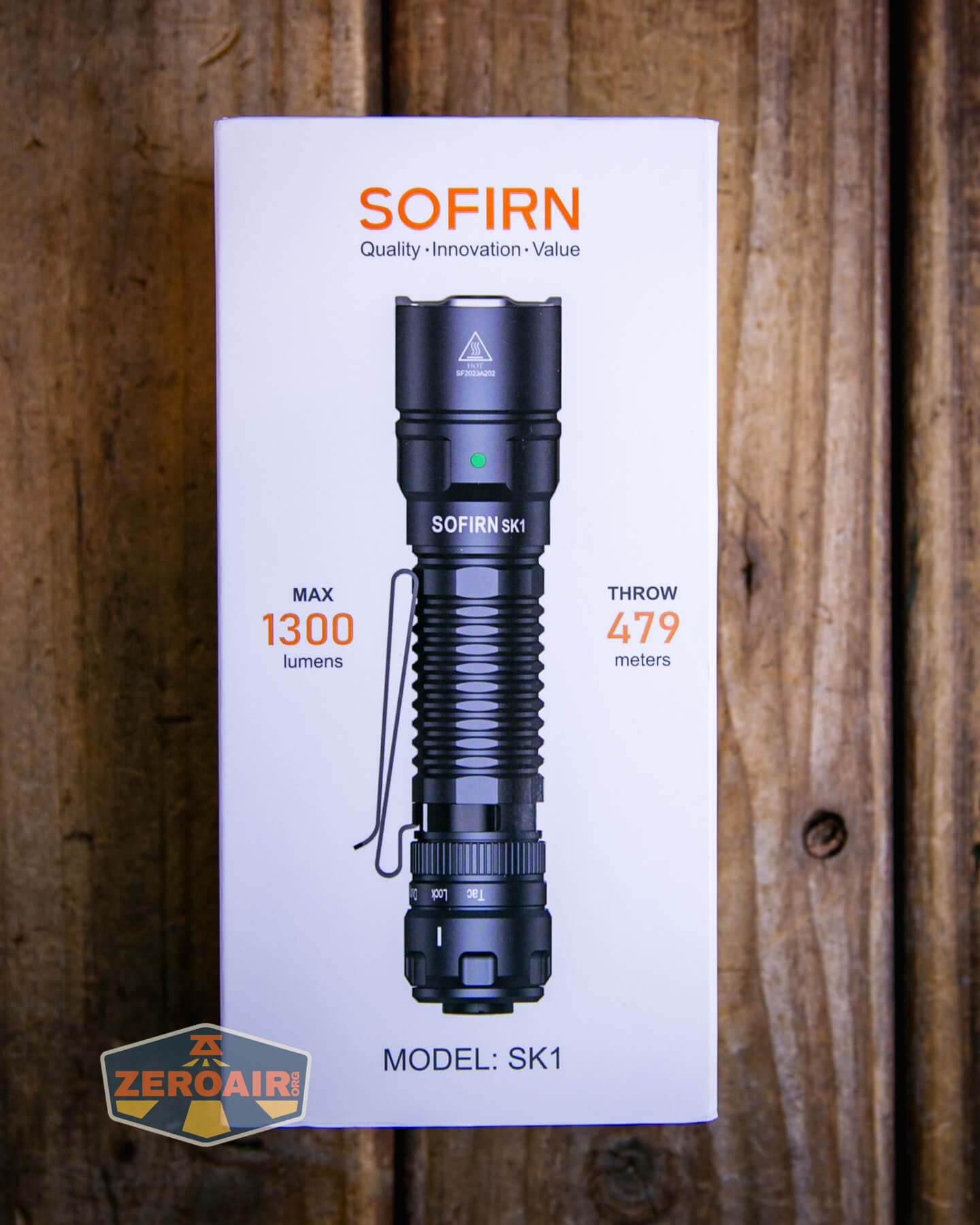 The image shows a product box for the Sofirn SK1 flashlight, featuring an image of the flashlight and specifications: max 1300 lumens, throw 479 meters, with the ZeroAir logo on the bottom left. The box is on a wooden surface.