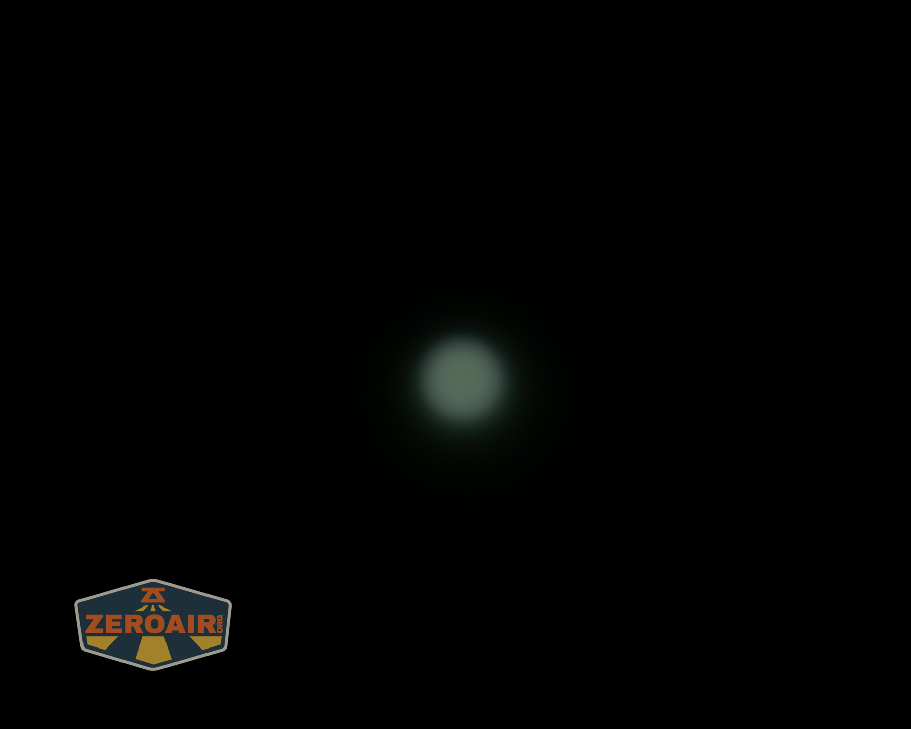 A faint, small, circular light source is centered against a completely dark background. The ZeroAir logo is visible in the bottom left corner.
