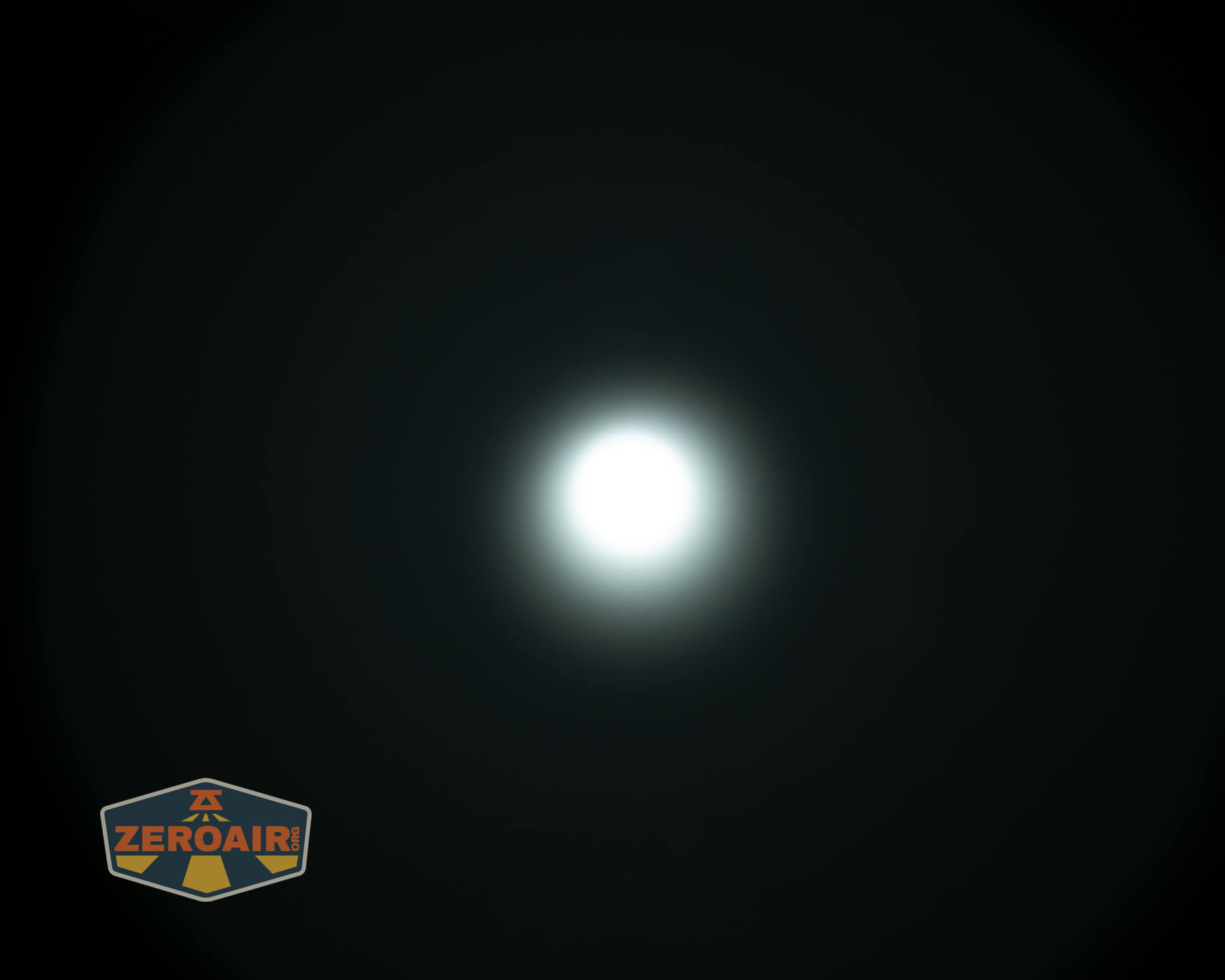 A bright white circular light is centered against a dark background, with a faint halo around it. The ZeroAir logo appears in the lower left corner.