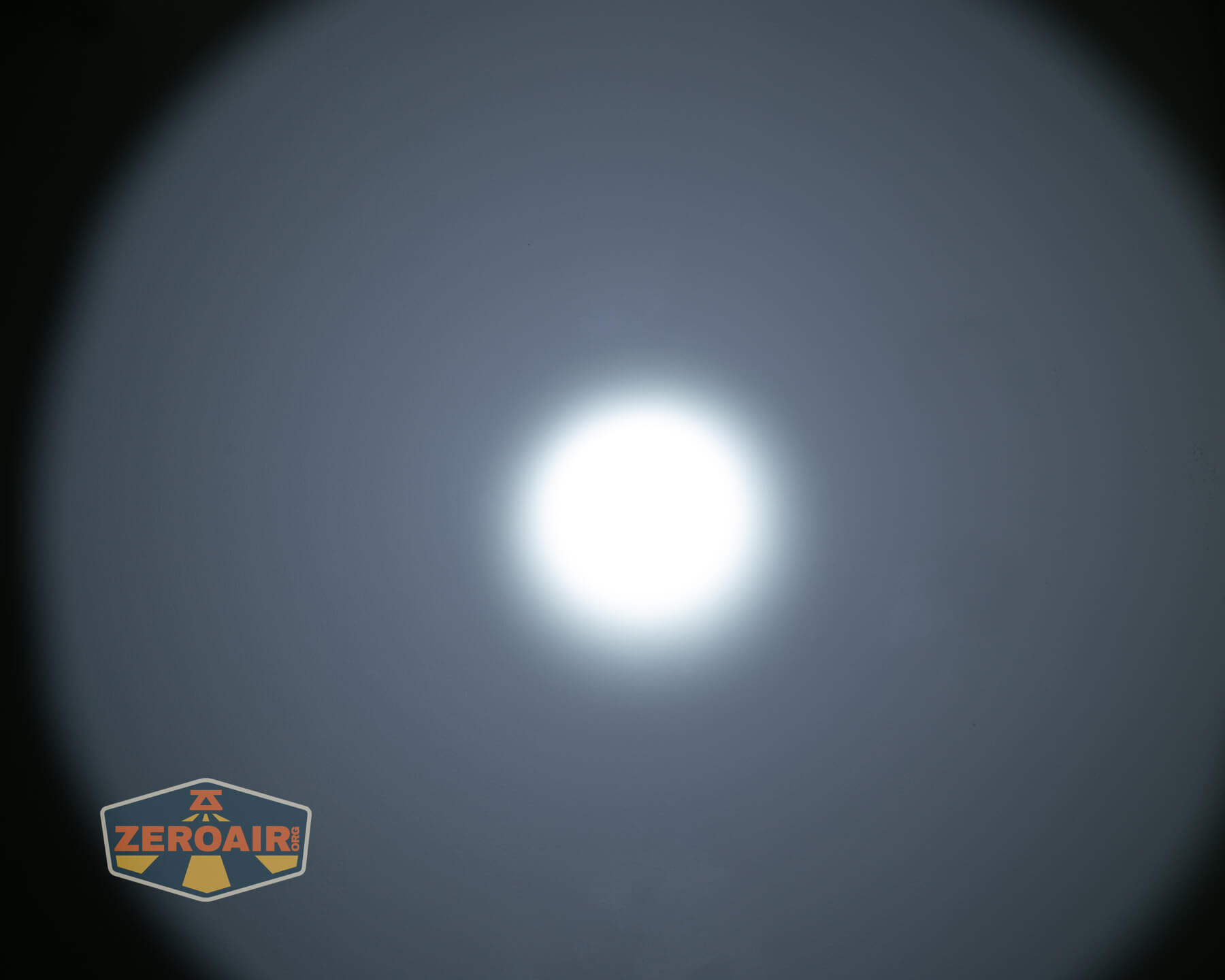 A bright white circular light appears in the center of a dark background, creating a gradient halo effect. A logo reading ZEROAIR is visible in the lower left corner.