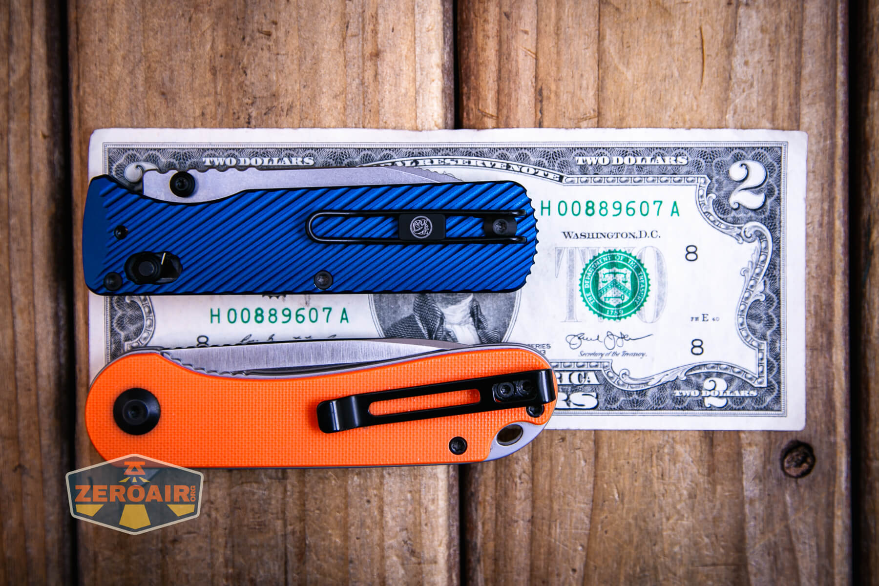 Vosteed Vombat Crossbar lock knife on a two dollar bill compared to Civivi Elementum in orange