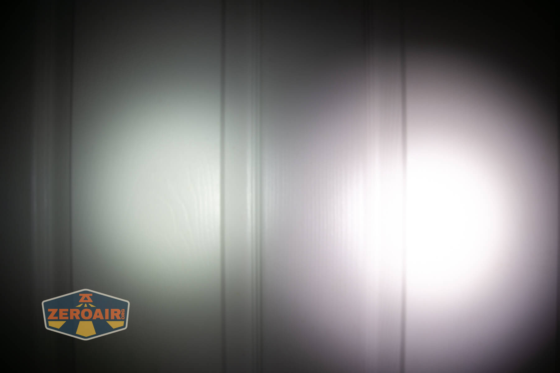 Nitecore TUP2 rechargeable keychain flashlight beamshots on door compared to nichia 219b