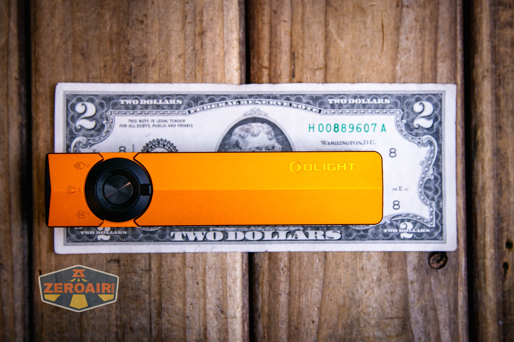 Olight ArkPro Orange flashlight on two dollar bill