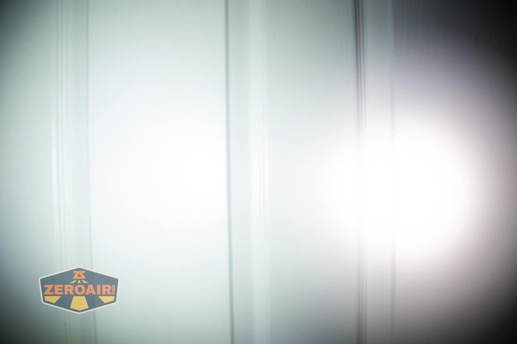 Olight ArkPro Silver flashlight beamshots on door compared to nichia 219b