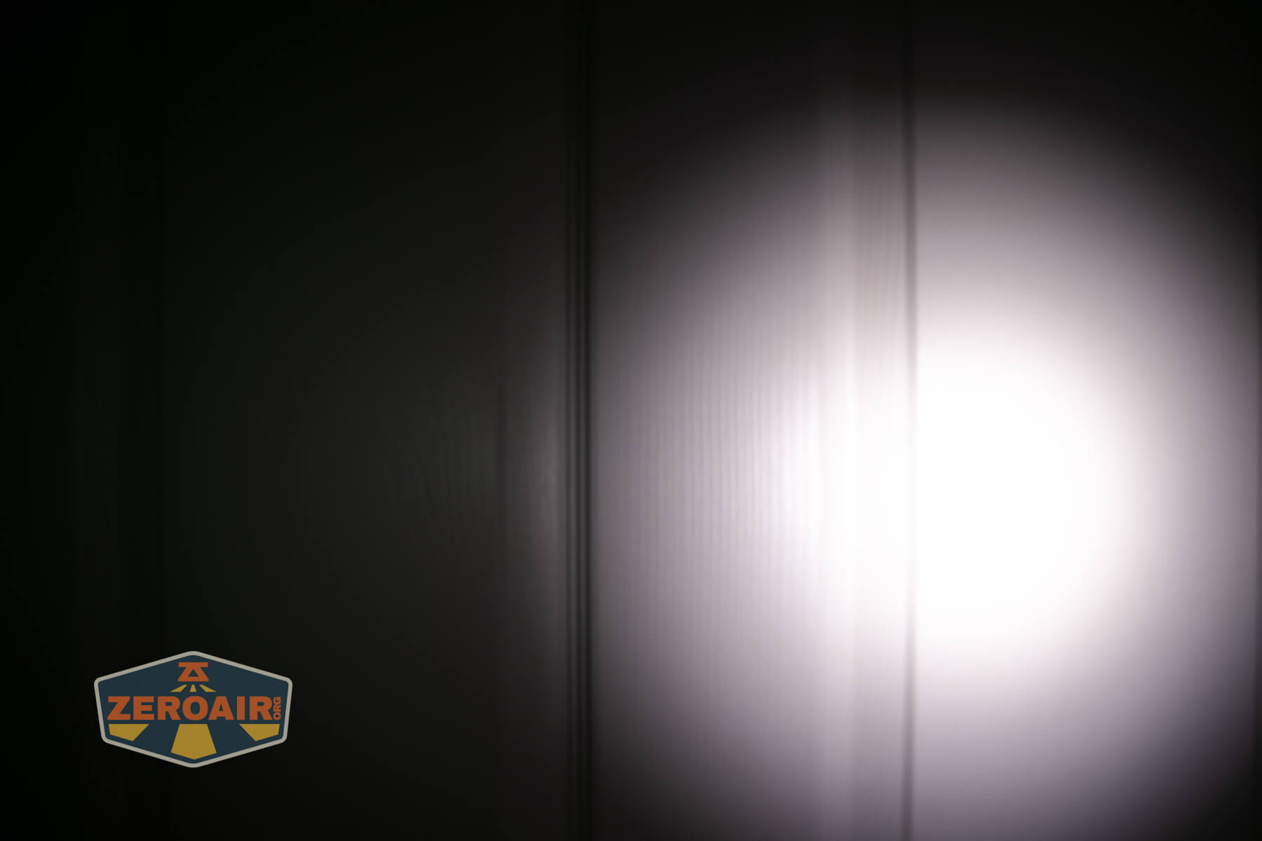 Olight ArkPro Ultra flat EDC flashlight beamshots on door compared to Nichia 219b