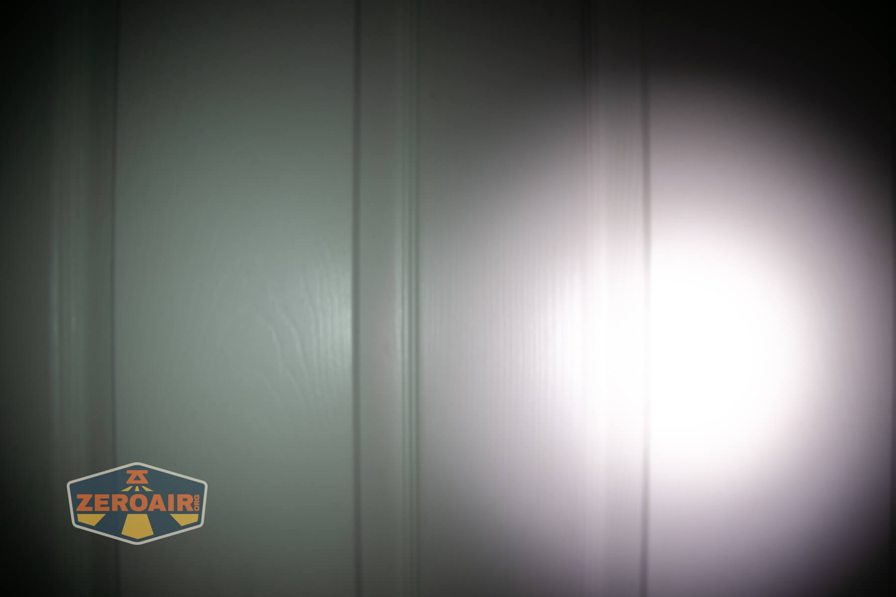 Olight ArkPro Ultra flat EDC flashlight beamshots on door compared to Nichia 219b