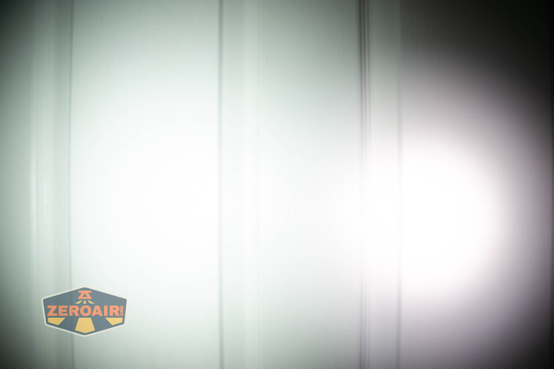 Olight ArkPro Ultra flat EDC flashlight beamshots on door compared to Nichia 219b