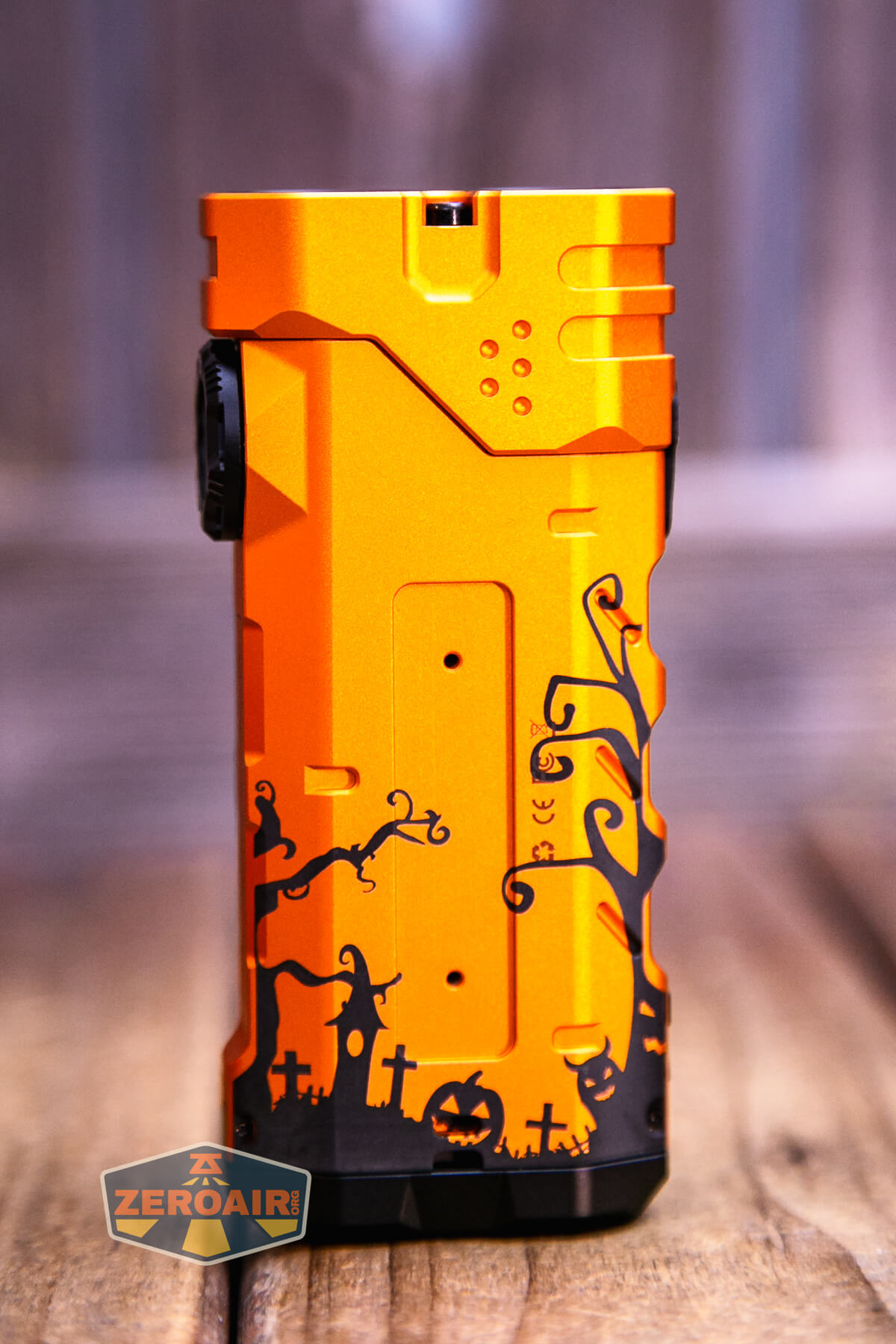 An orange rectangular flashlight features a black Halloween-themed design with silhouettes of a witch, pumpkins, gravestones, trees, and bats. The ZeroAir logo appears in the bottom left corner.