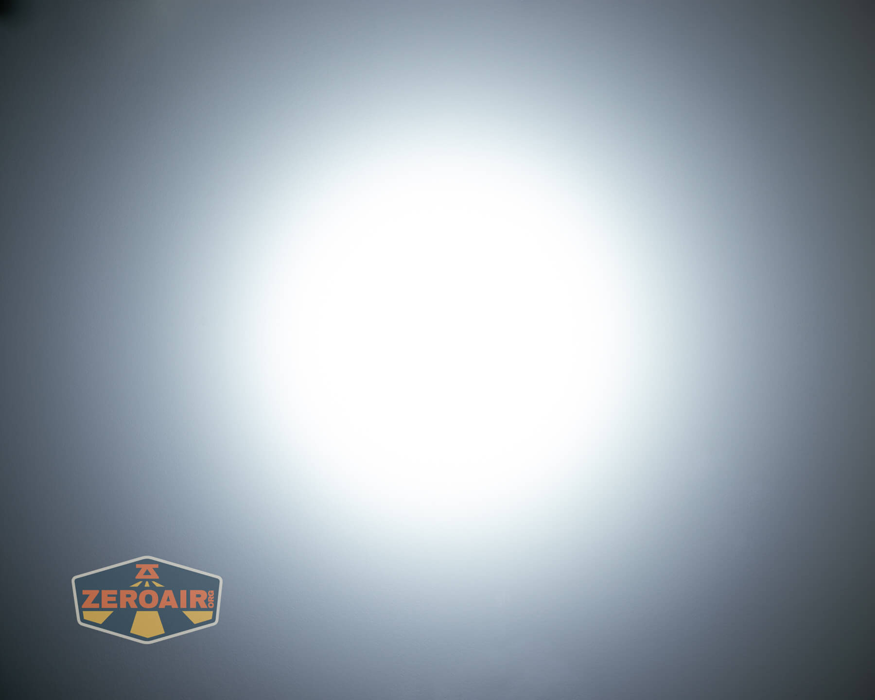 A bright white circular light beam is centered on a gray background, creating a gradient effect. A logo with the text ZeroAir appears in the bottom left corner of the image.