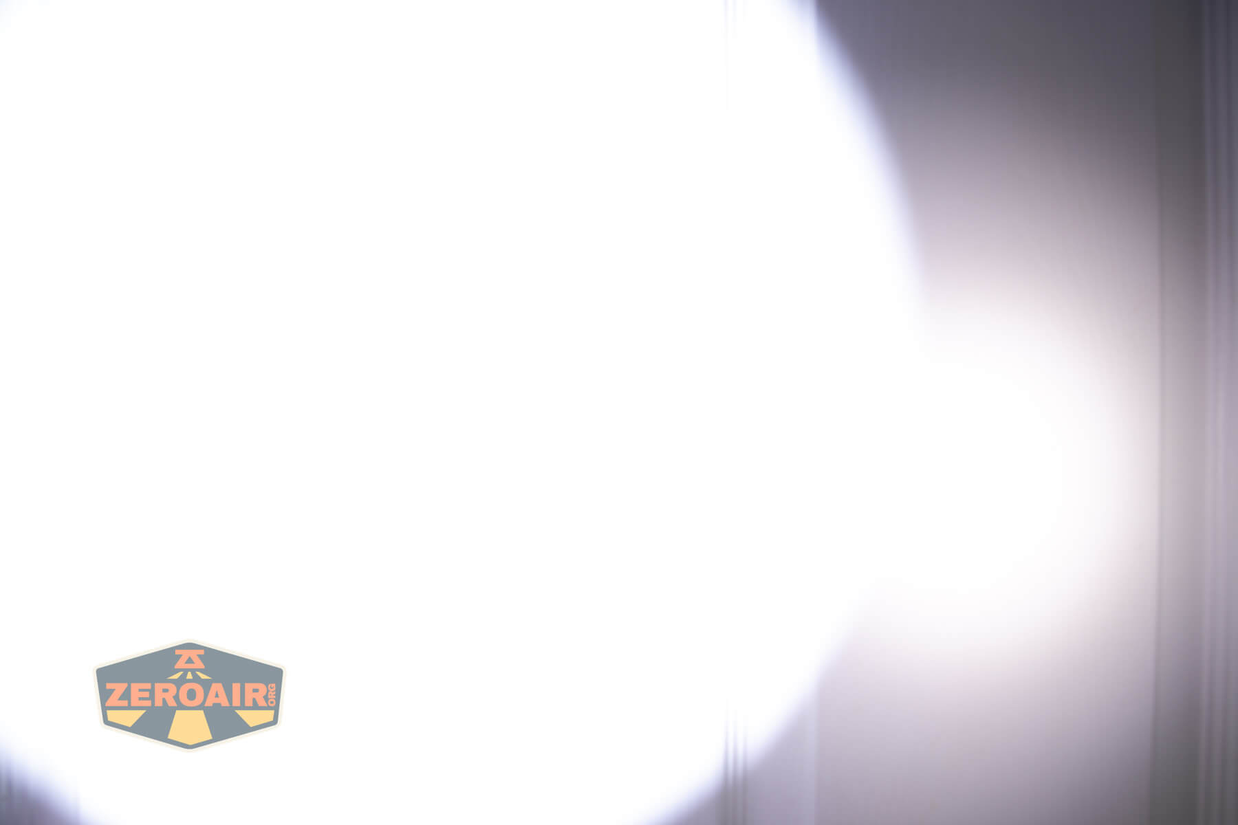 A bright white flashlight beam is shining on a smooth, light-colored wall. The ZeroAir logo is visible in the bottom left corner of the image.