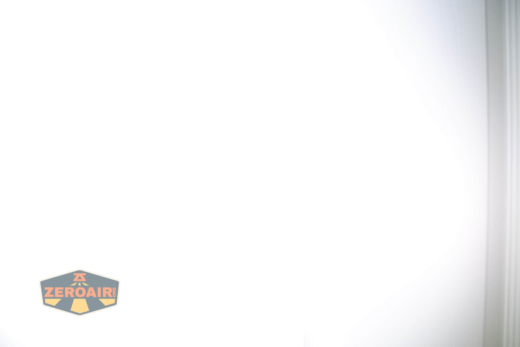 A mostly white, overexposed image with a faint outline of a vertical structure on the right and a ZeroAir logo with orange and yellow text on a dark shield in the lower left corner.