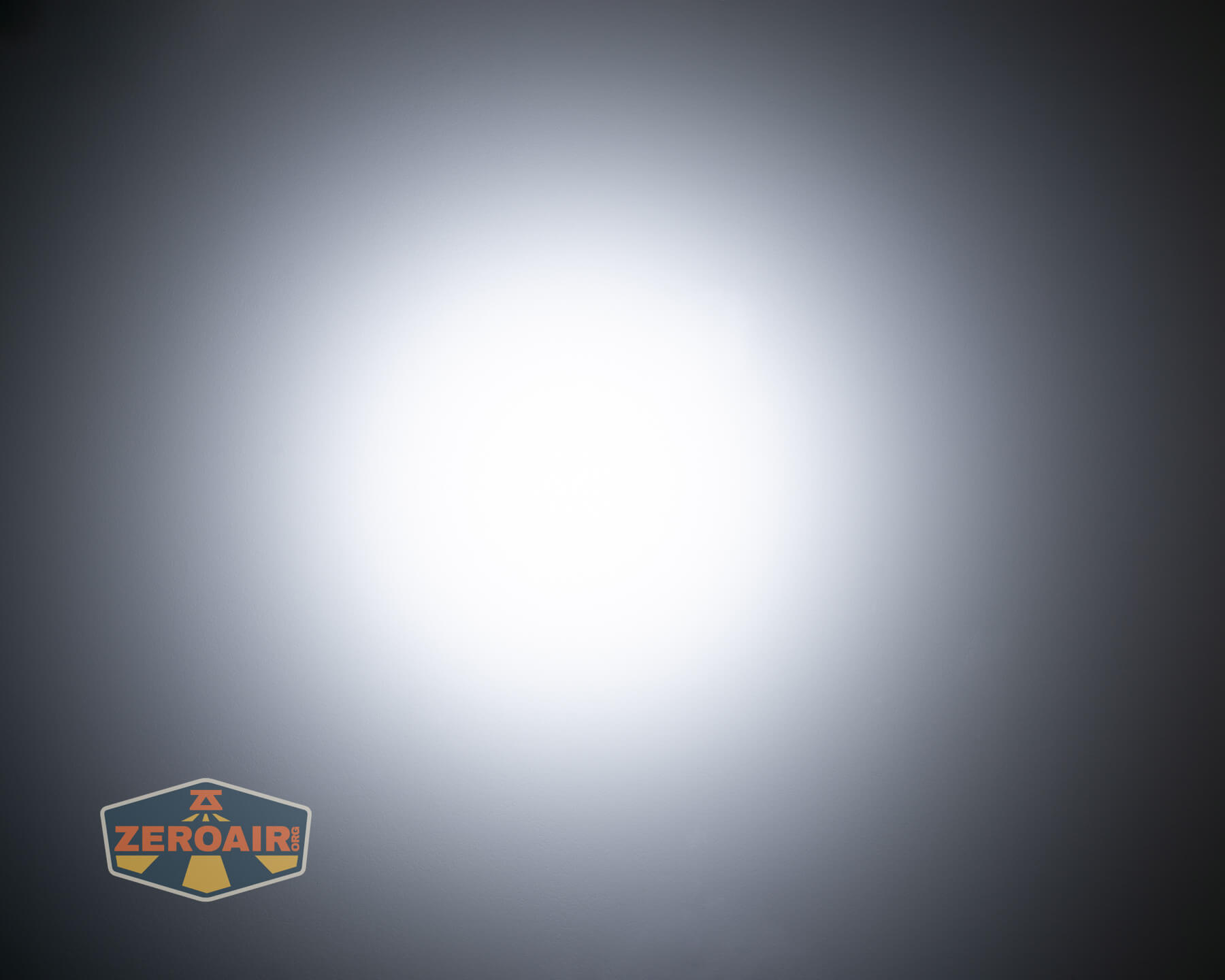 A bright white circular light is centered against a dark gradient background. A small logo with the text ZEROAIR appears in the lower left corner.