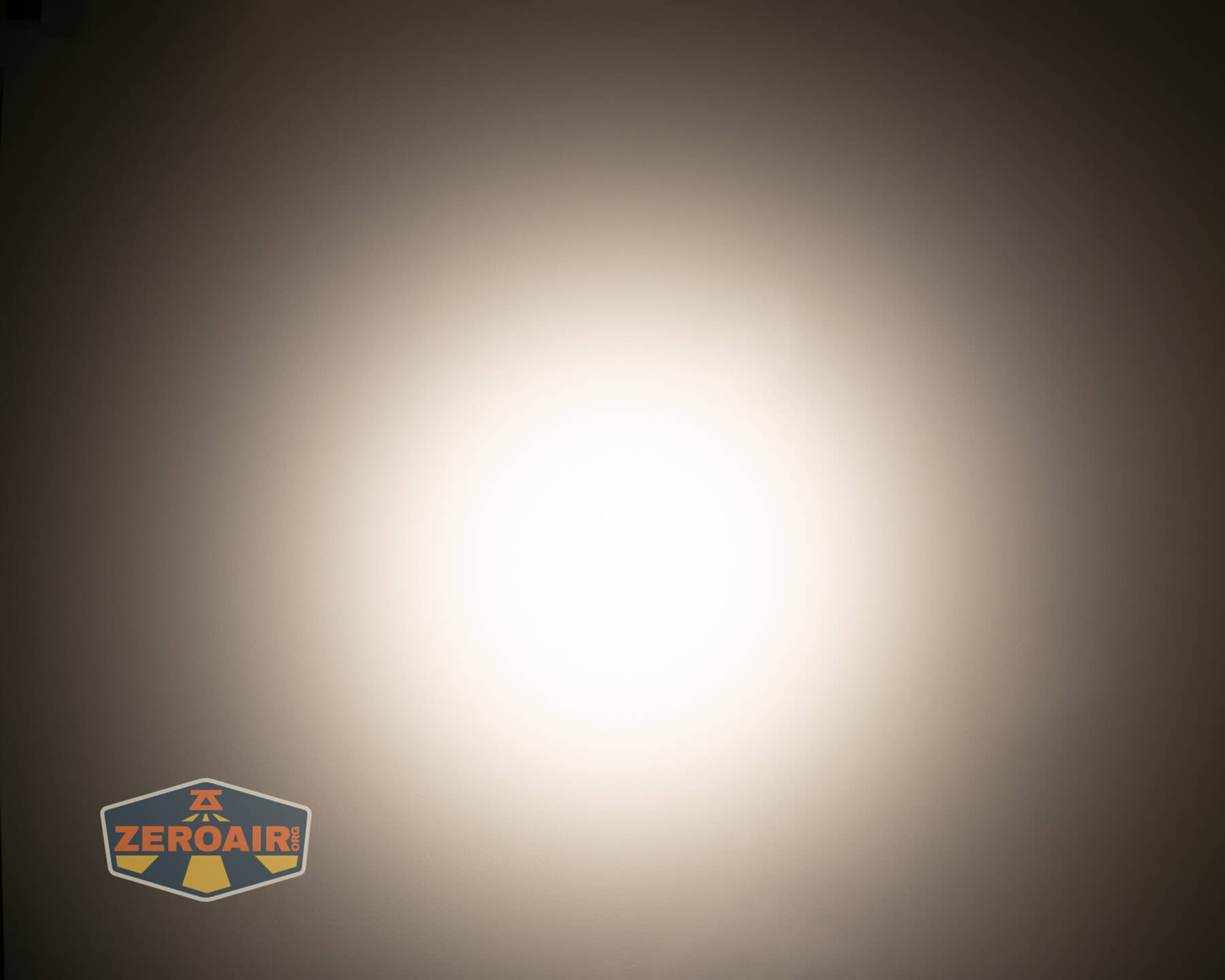 A bright, circular white light is centered against a dark, gradient background. The image has a ZeroAir logo in the bottom left corner.