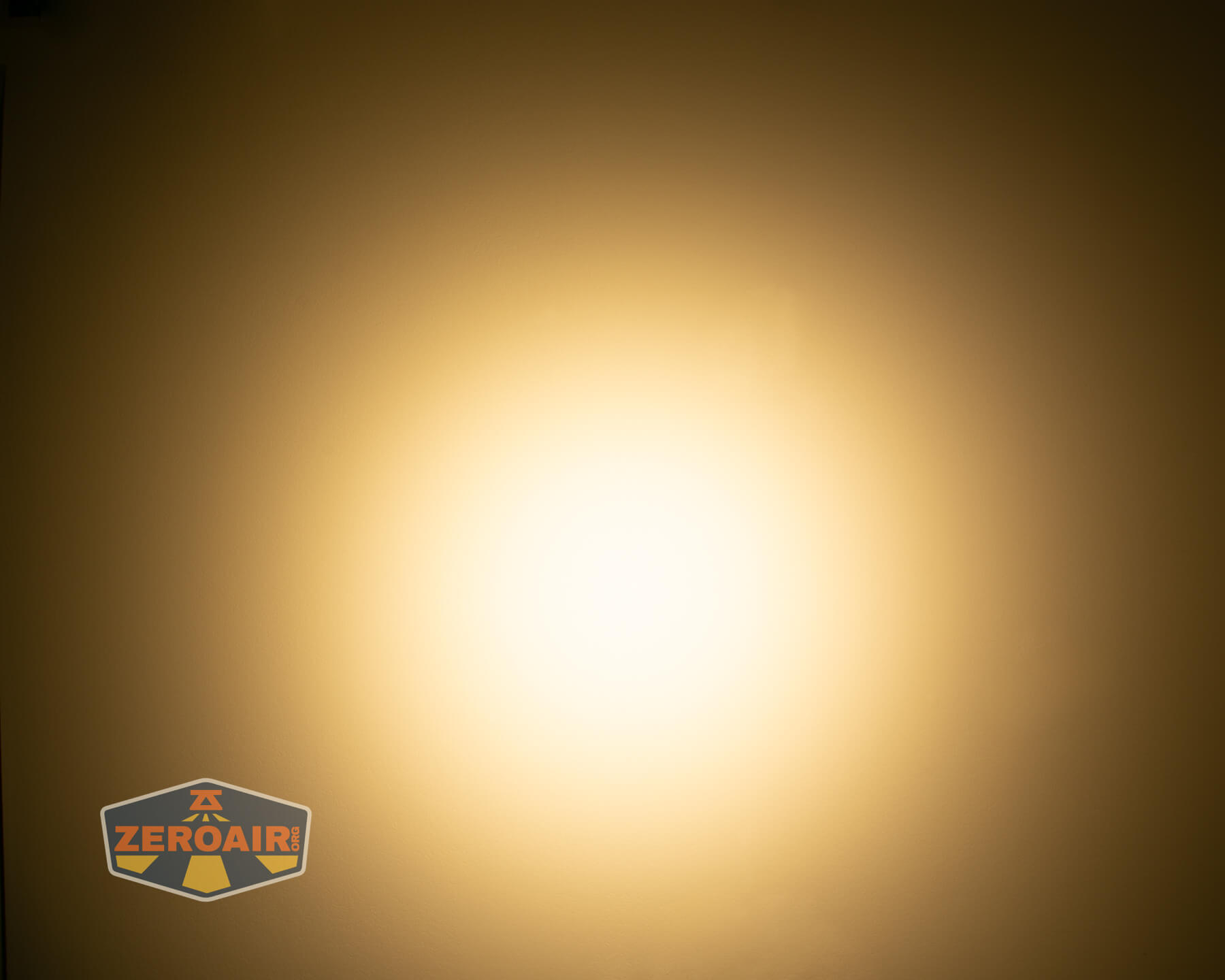 A bright, circular warm white light shines in the center of a brownish background. In the lower left corner, a ZeroAir logo is visible.