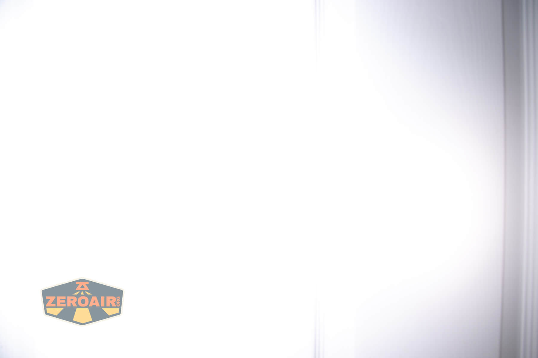 A mostly white, overexposed image with faint vertical lines and a faint shadow on the right side; a small ZeroAir logo appears in the lower left corner.