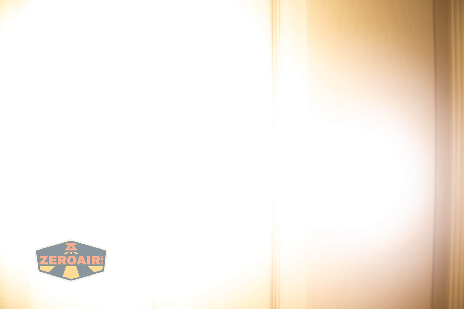 A bright, overexposed image with vertical light streaks and a strong white glare. In the bottom left corner, there is a ZeroAir logo with a yellow road graphic and red letters.