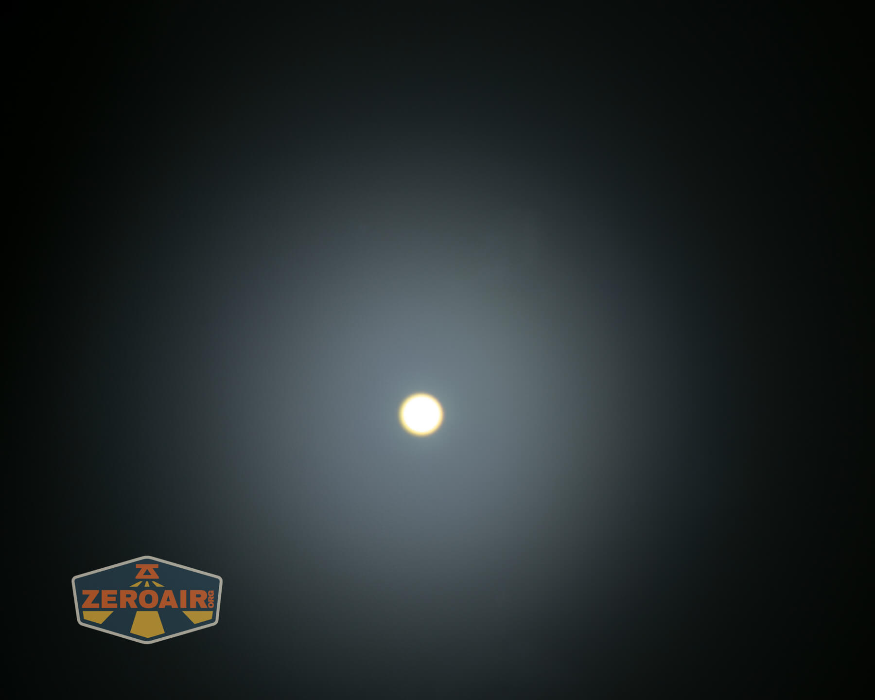 A circular white light source appears in the center of a dark background with a soft halo effect. A ZEROAIR logo is visible in the bottom left corner.